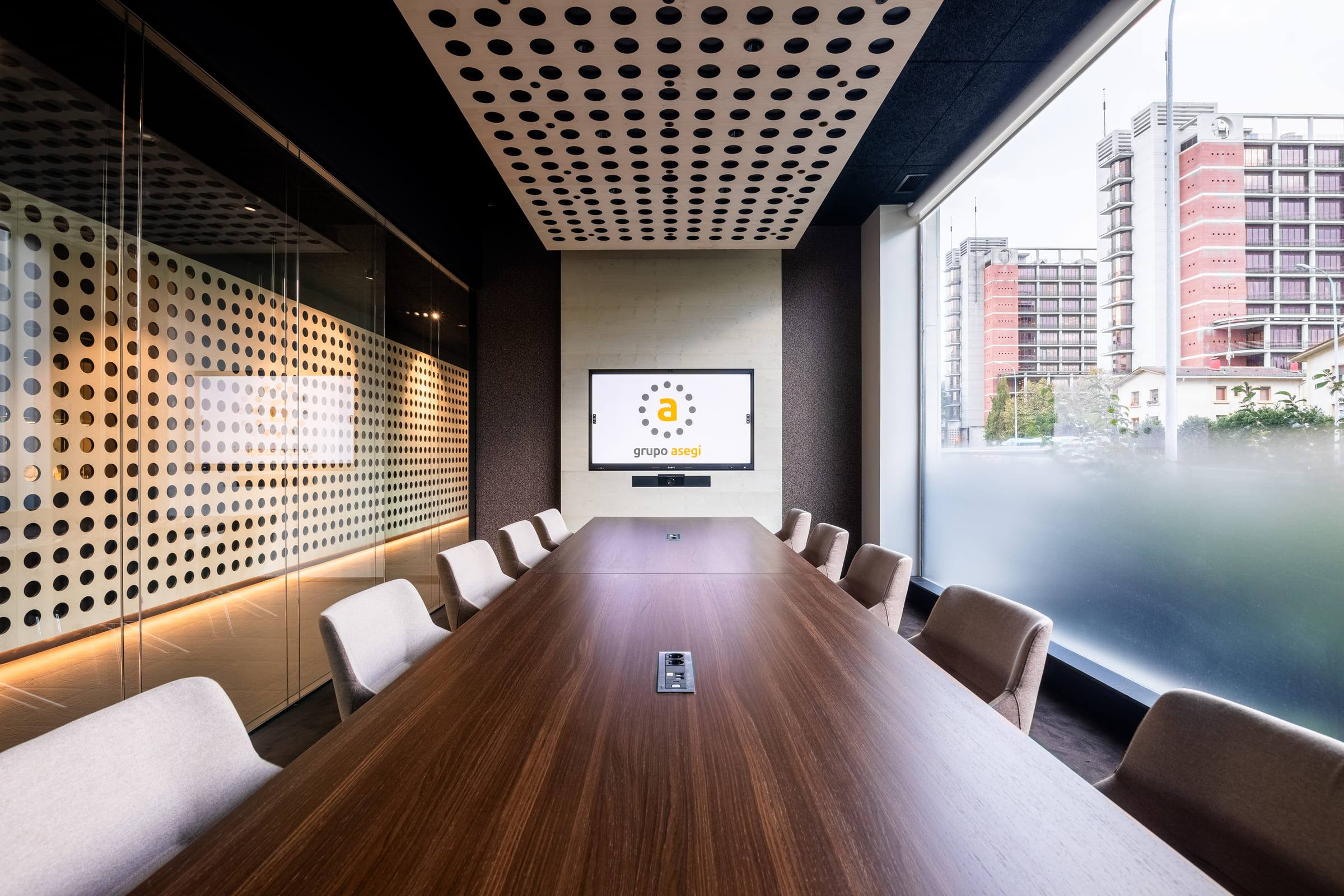 Sala de reuniones de Grupo Asegi en Donostia, con techo perforado y pantalla de presentación